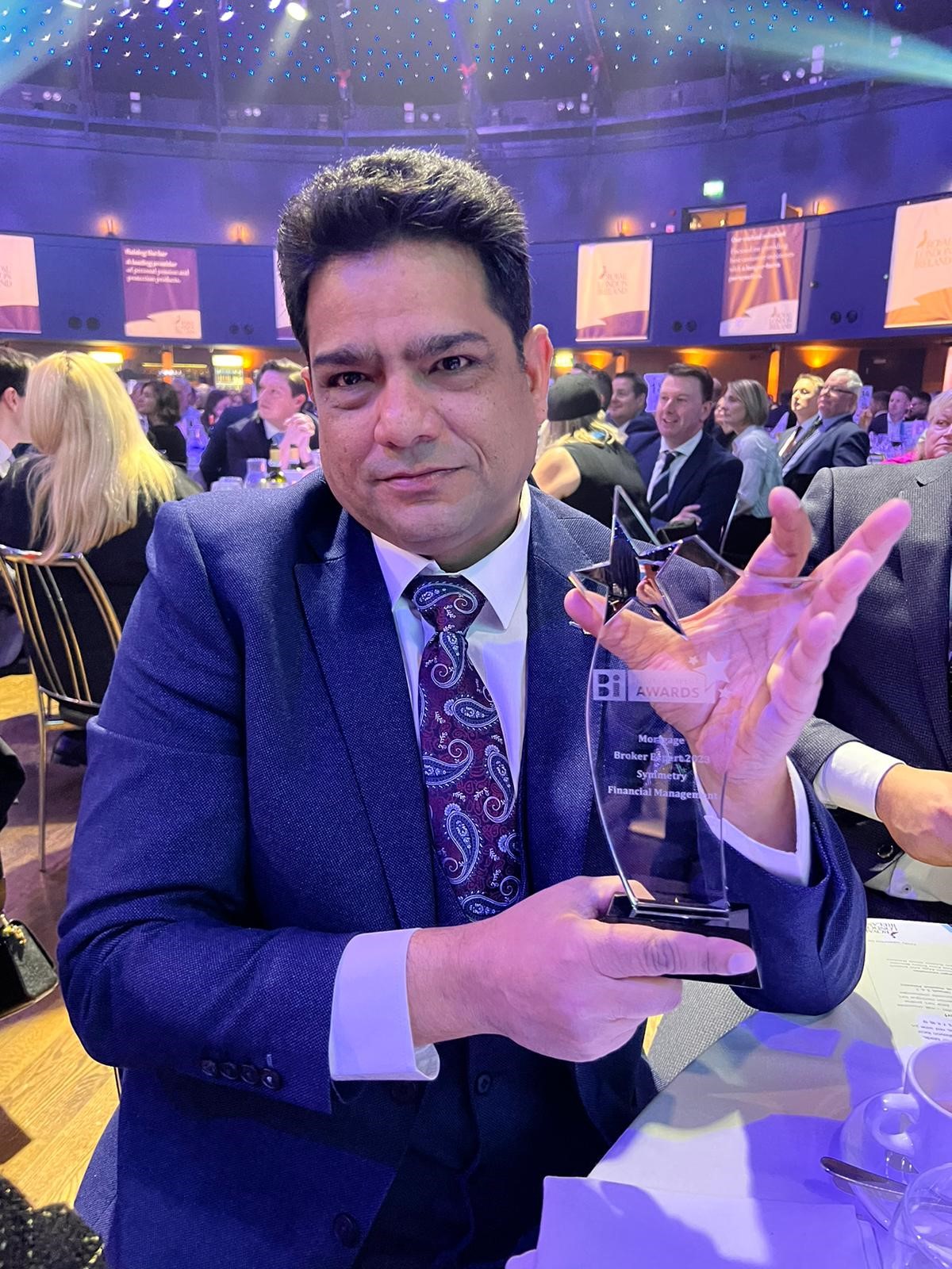 Kanwar seated at table with Brokers Ireland Mortgage Broker Expert Award 2023 trophy